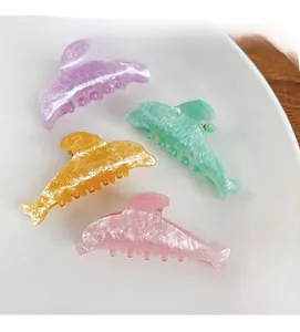 Detailed macro view of dolphin hair clips featuring glitter resin in pastel macaron colors