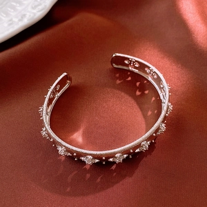 Detail of silver cuff bracelet with starburst zircon inlay on a dark silk backdrop