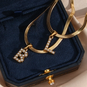 Detailed view of 18K gold-plated snake chain featuring B and L pearl letter pendants