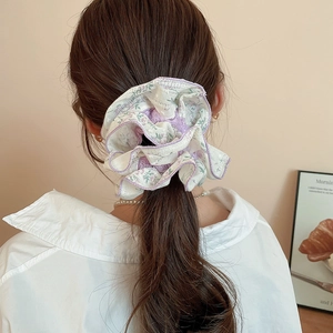 Detailed view of a purple floral lace hair scrunchie styled on a woman's ponytail