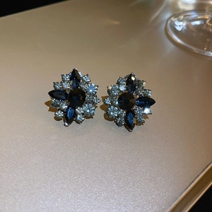 Detailed close-up of dark blue flower stud earrings with shimmering crystal accents