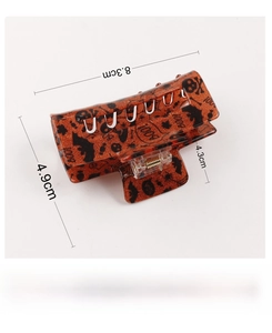 Detailed size view of orange PVC Halloween hair claw with black bat and skull prints