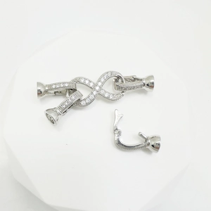 Silver infinity double-row necklace clasp with cubic zirconia on a white pedestal