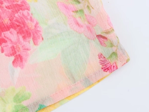 Close-up of floral poplin shirt fabric featuring gold buttons and precise stitching