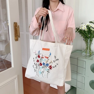 White canvas tote bag with multi-color floral embroidery and long handles