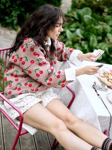 Women's pink cherry knit sweater with crew neck and long sleeves in outdoor setting