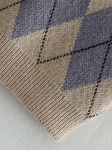 Close-up of diamond argyle knit pattern and ribbed hem on a cropped vest top