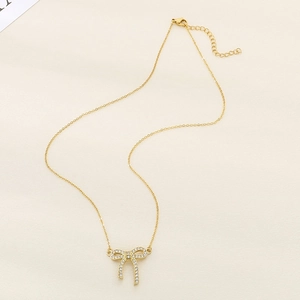 Elegant gold-tone stainless steel necklace with a sparkling bow pendant and zircons