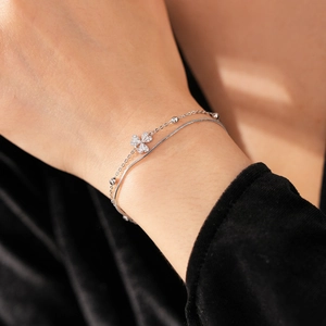 Detailaufnahme eines zweilagigen Silber-Kleeblatt-Armbands mit Zirkonia-Steinen am Handgelenk