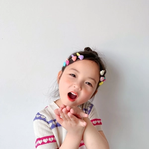 Close-up of a young girl wearing colorful heart-shaped candy color hair clips in hair