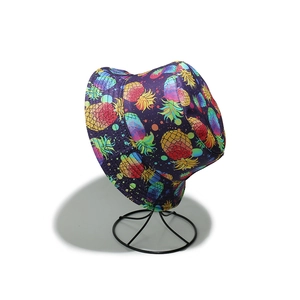 Detail of purple bucket hat with colorful pineapple patterns on a metal stand
