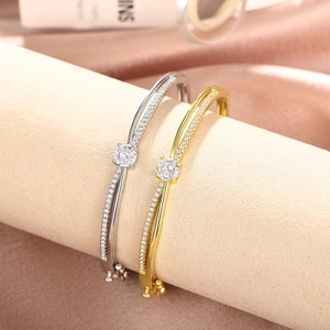 Detail shot of elegant crossover gold bracelet with round zircon on silk background