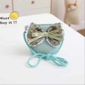 Detail of light green woven girls' straw bag with floral bow and lace decoration