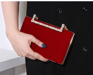 Detailaufnahme einer luxuriösen roten Samt-Abendtasche mit einem Griff aus Strass