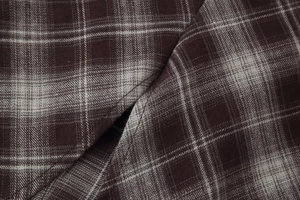Close-up of the woven plaid fabric texture in dark brown and grey for long sleeve shirt