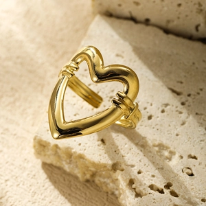 Detail of hollow heart ring in gold finish placed on beige travertine stone blocks