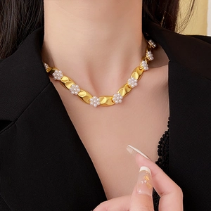 Detail of vintage gold necklace with white pearl flower worn by model in soft lighting