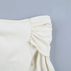 Gros plan détaillé du tissu en maille plissée crème avec couture d'épaule à volants chic