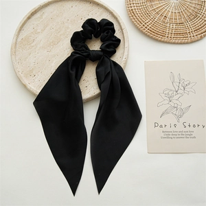 Detail of elegant black satin ribbon scrunchie on a decorative stone tray with props