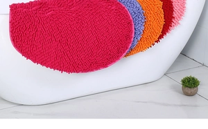 Detail of semi-circular chenille bath mats in multiple colors hanging on a white bathtub
