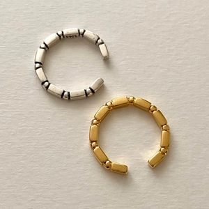 Detailed view of silver and gold S925 bamboo textured adjustable rings on textured paper