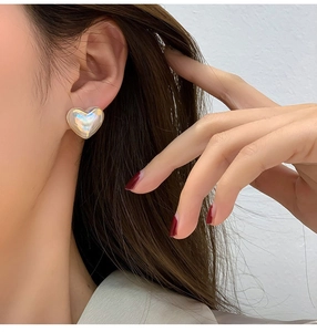 Primer plano de pendientes de perlas iridiscentes en forma de corazón en una modelo