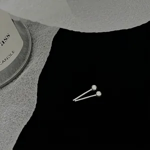 Detailed close-up of 2.5mm silver bead stud earrings on a dark minimalist background