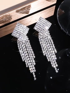 Macro shot of silver geometric square earrings with sparkling rhinestone tassels detail