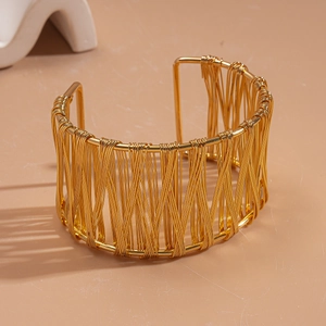 Close-up of golden woven wire mesh structure on a wide geometric open bangle bracelet