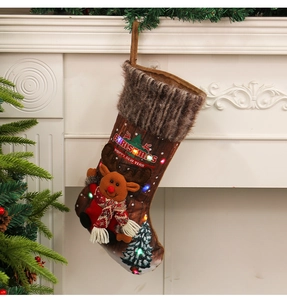 Hanging Christmas stocking with reindeer doll and LED lights on a white fireplace