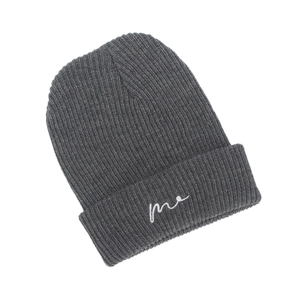 Detail shot of dark grey knit beanie featuring white cursive me letter embroidery