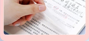 Close-up of hand peeling transparent sticky note revealing clear text on book page