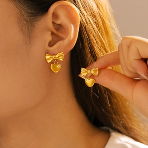 Gold stainless steel bow heart earrings with micro-inlaid stones on model