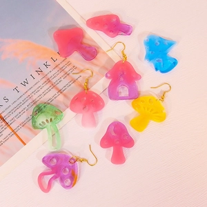Handmade colorful resin mushroom earrings and pendants with golden hooks on aesthetic background