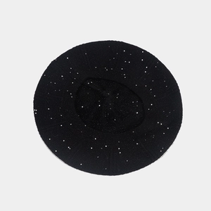 Detail shot of a black sequin beret hat showing sparkling fabric and knit texture