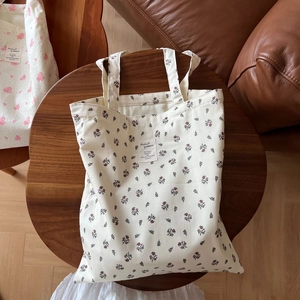 Flat lay of vintage floral cotton tote bag with artistic label on a dark wooden table