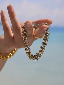 Close-up of dual-tone gold and silver heart-shaped metal bracelet on a model's hand
