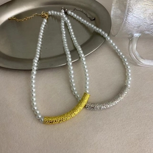 French style pearl necklaces with textured gold and silver tubes on beige background