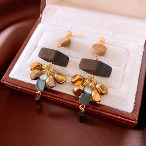 Detail of vintage geometric drop earrings with wood and tiger eye beads in a jewelry box