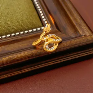 Gold-plated snake-shaped ring with sparkling crystals on vintage leather background