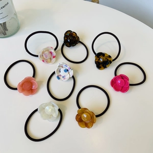 Set of eight floral camellia hair ties in diverse resin colors on a white background