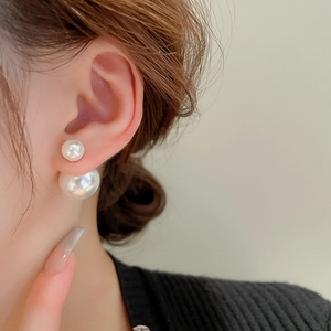 Close-up of double-sided pearl earrings worn by a model for a chic and elegant look