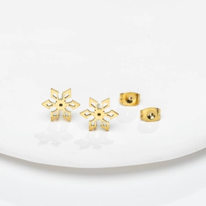 Detailed view of 18K gold plated stainless steel snowflake stud earrings on white ceramic