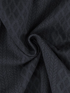 Dettaglio ravvicinato di tessuto grigio antracite con trama jacquard a rombi geometrici