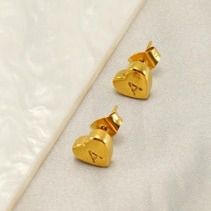 Boucle d'oreille cœur en acier doré avec lettre A gravée sur une assiette blanche