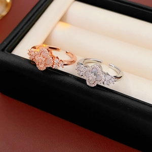 Detailed close-up of clover-shaped zircon and mother-of-pearl rings in a jewelry box