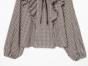 Detail of ruffled collar and drawstring neckline on brown plaid checkered blouse