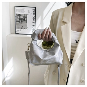 Close-up of silver crescent handbag with ruched handle and heart-shaped pendant