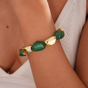 Close-up of green glitter resin and gold metal beads on a stylish women's bracelet