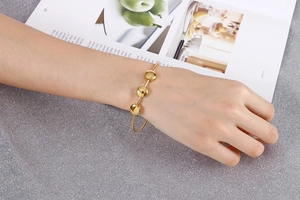 Detailed view of a gold stainless steel open bangle featuring three round disc charms